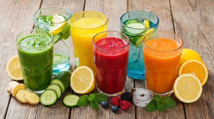 6 natural detox drinks to burn belly fat, with fresh fruits and a measuring tape.